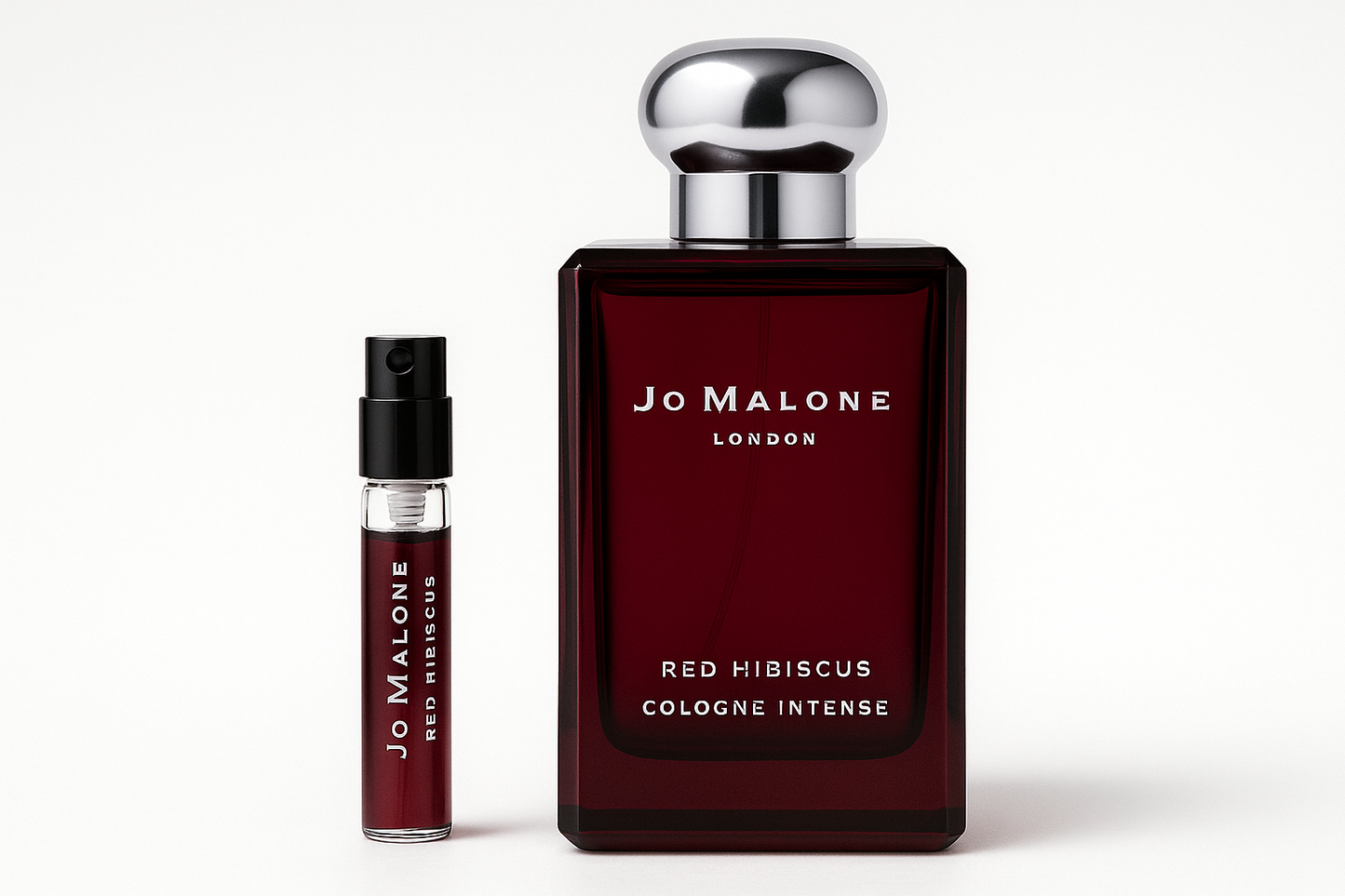 عينة من عطر Jo Malone Red Hibiscus Cologne Intense سعة 2 مل بجوار زجاجة عطر سعة 100 مل من عطر Jo Malone Red Hibiscus Cologne Intense والتي تحتوي على كتابة باللون الأبيض على زجاجة حمراء داكنة